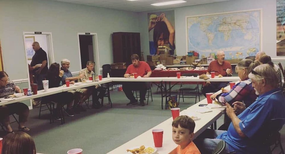 Fellowship gathered around the table beneath a world map