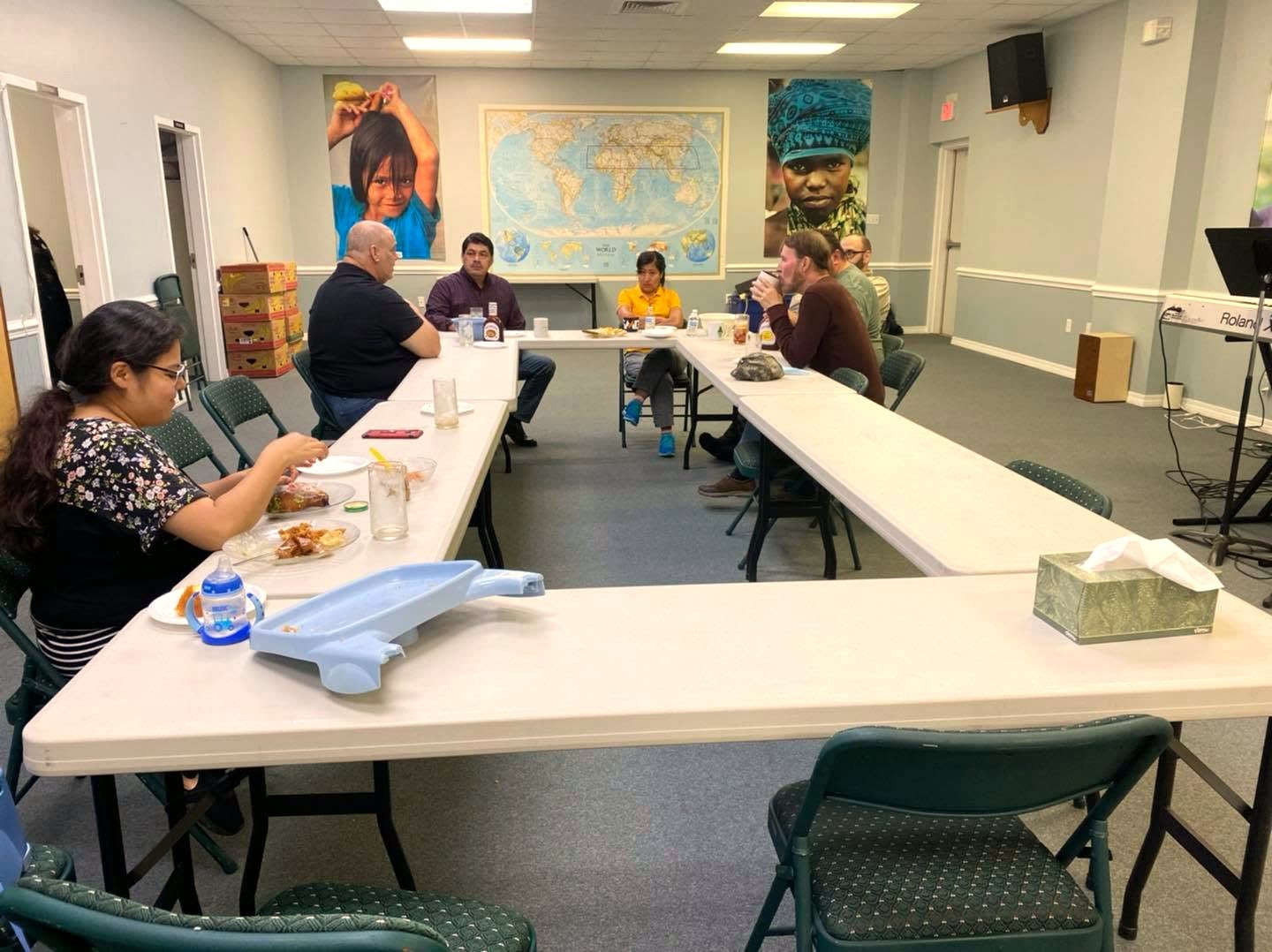Fellowship gathered around the table beneath a world map